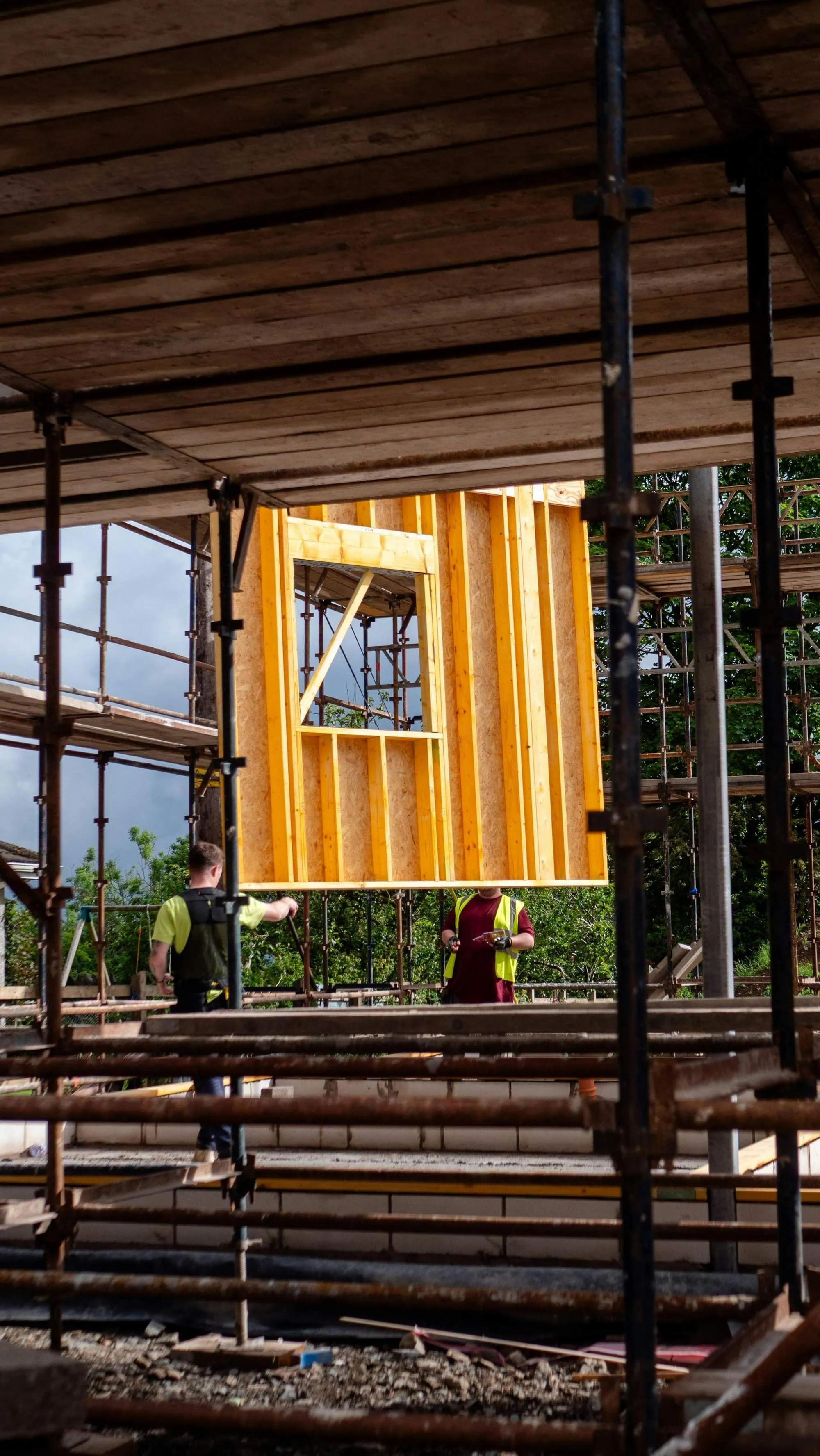 Two framers lifting a stud wall on scaffolding