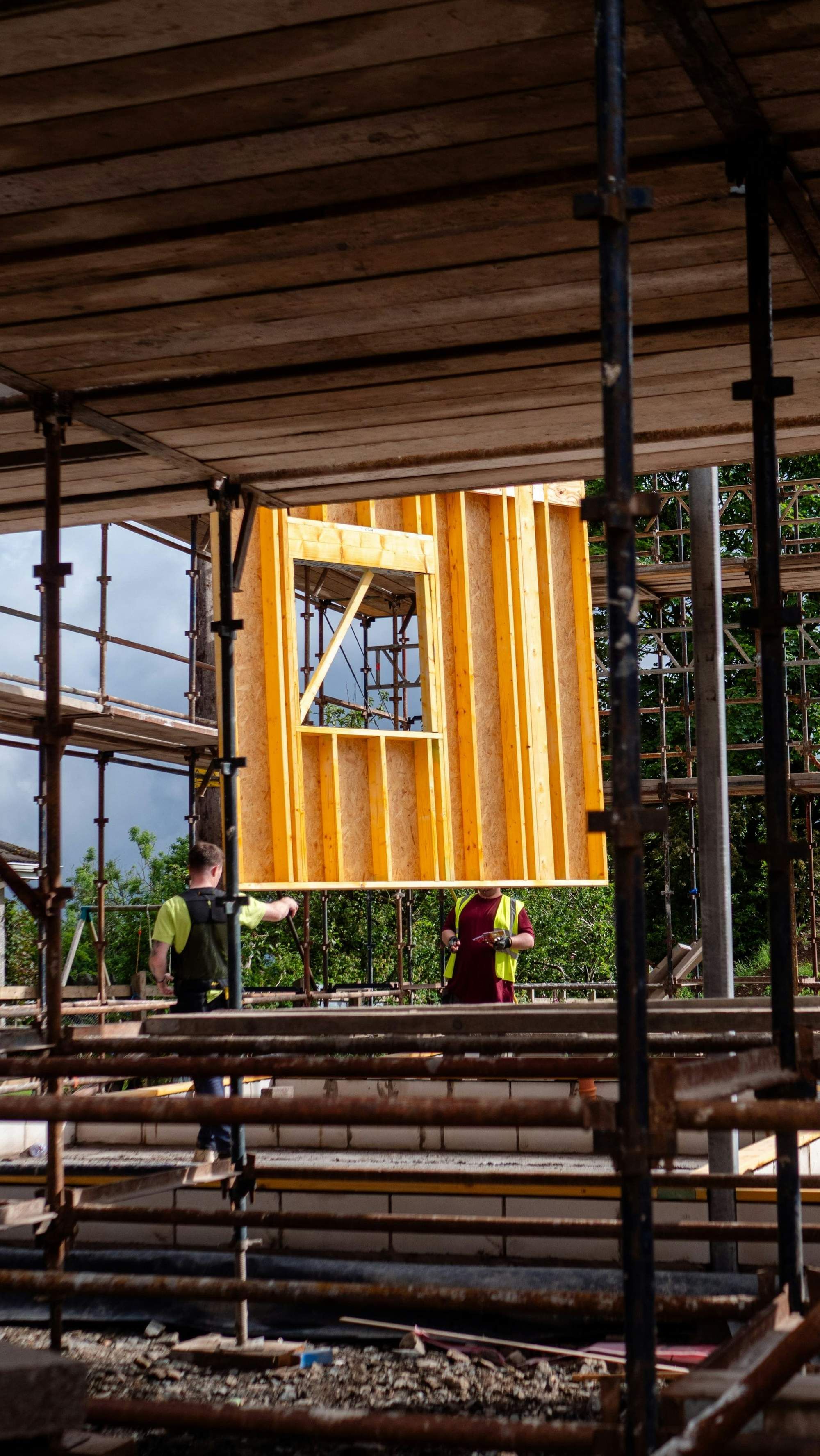 Two framers lifting a stud wall on scaffolding