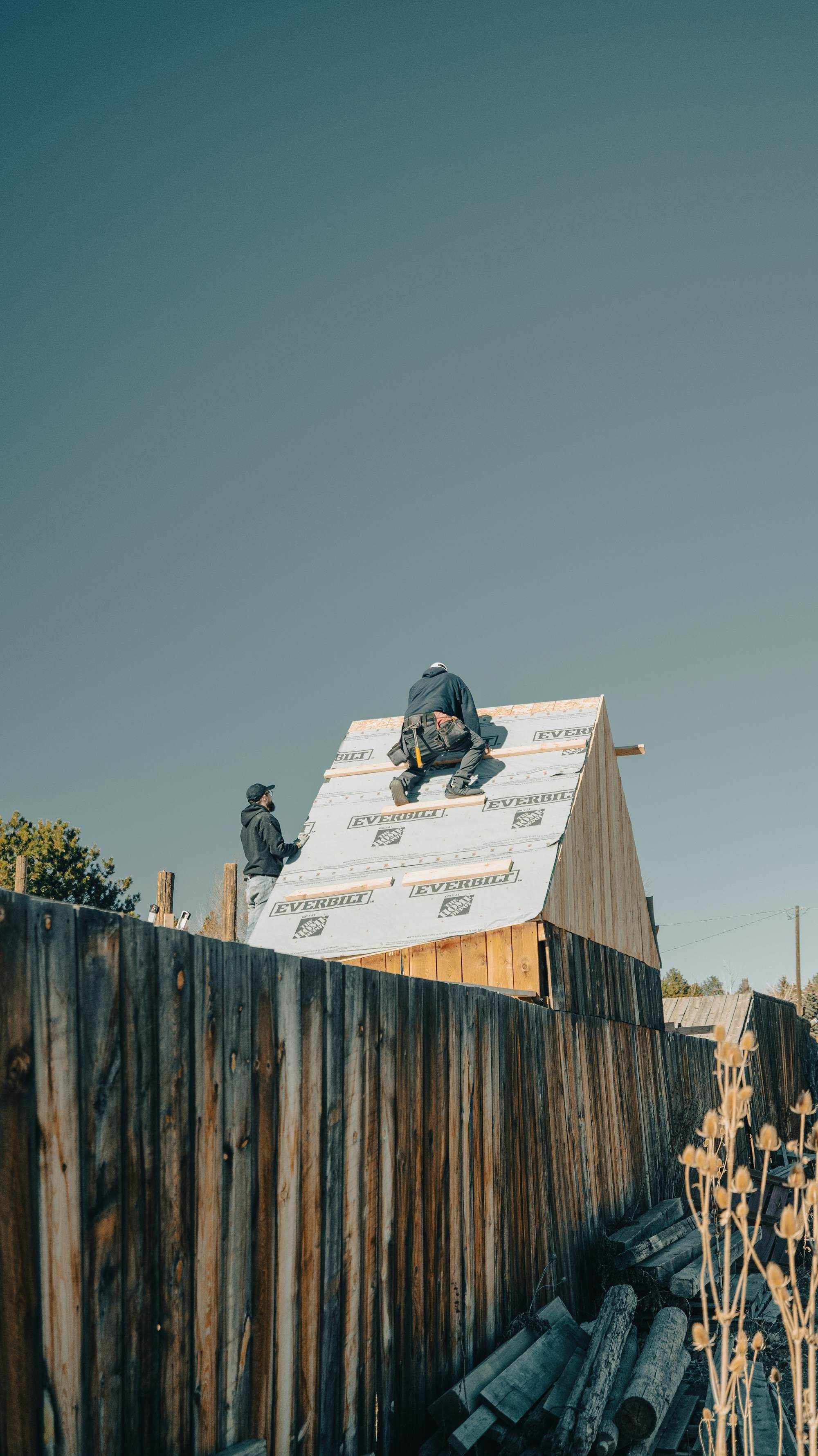 Framers sheathing a new roof under a clear sky