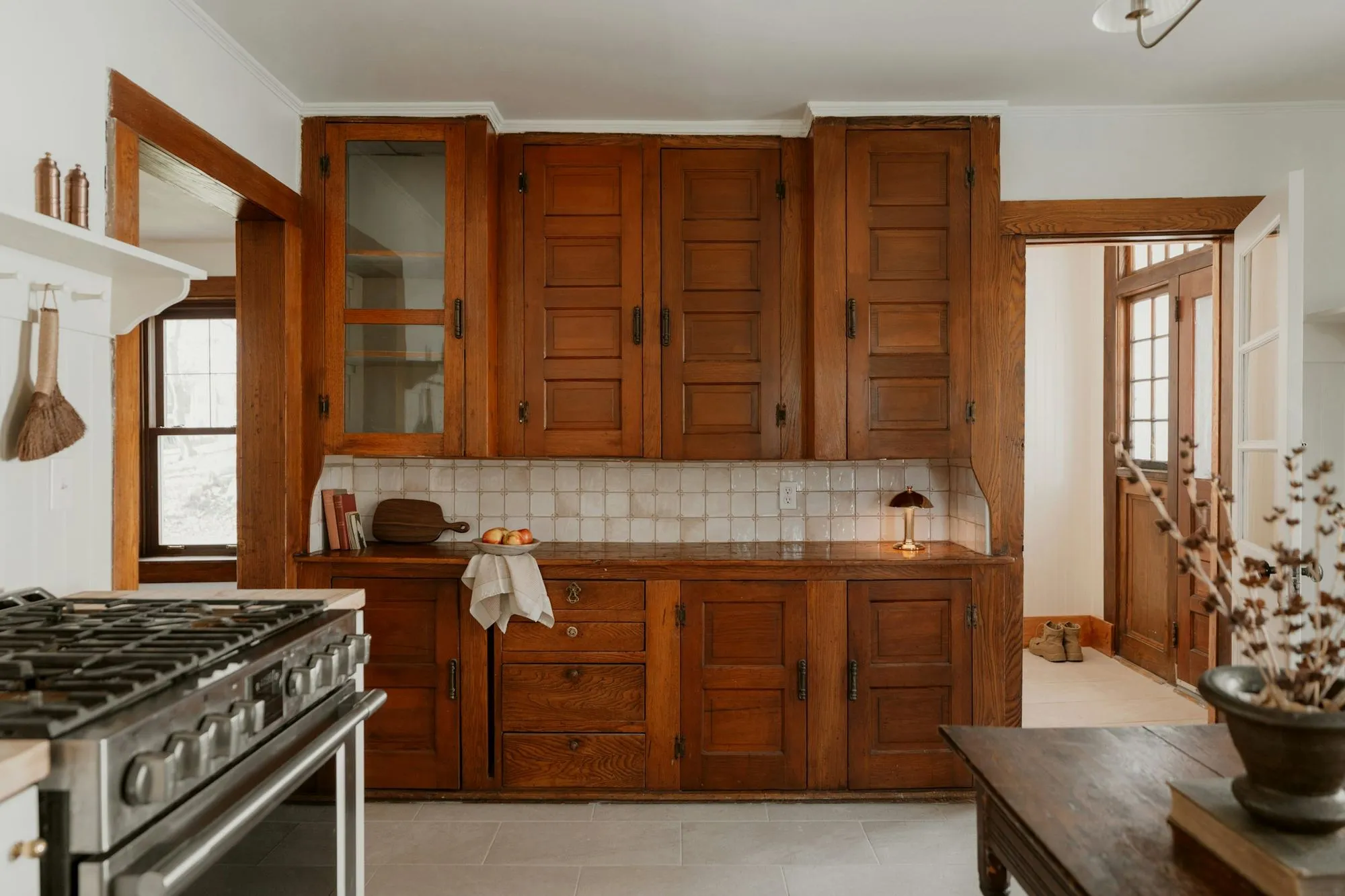 A comparable kitchen before a remodel, with worn wood cabinetry and a tiled backsplash
