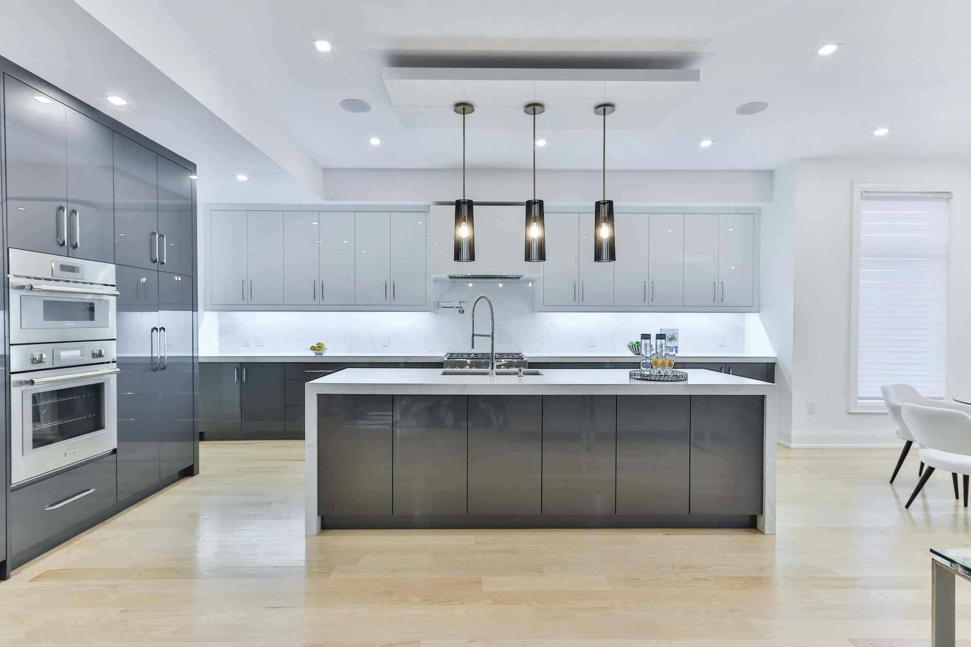 A finished grey high-gloss kitchen with a dark island and pendant lights